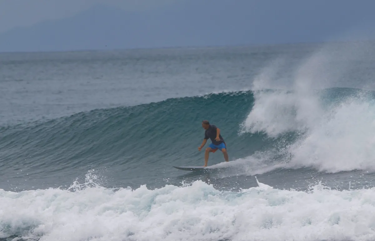 Surfer rides a peeling right wave with steady balance.