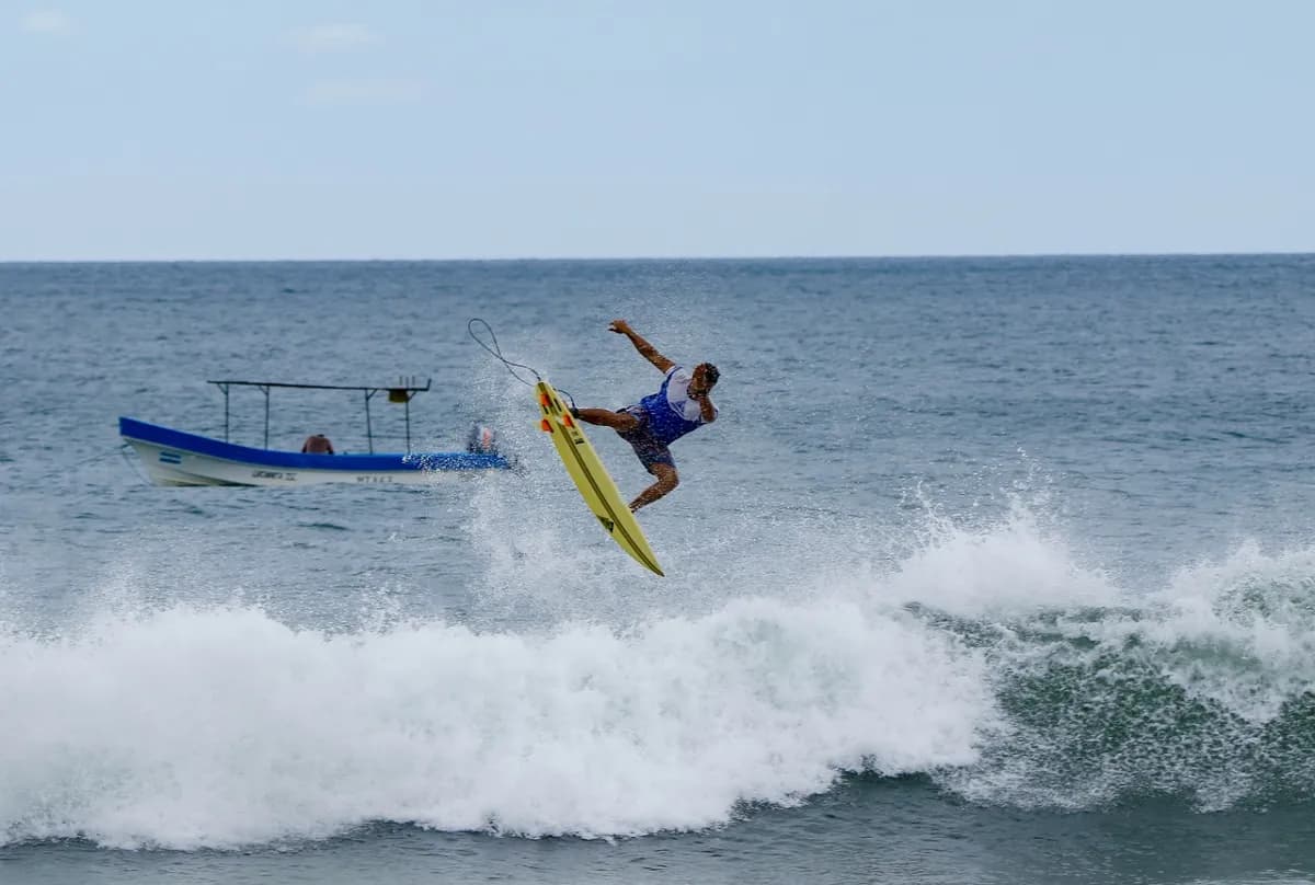 Surfer performs an aerial maneuver above a breaking wave.