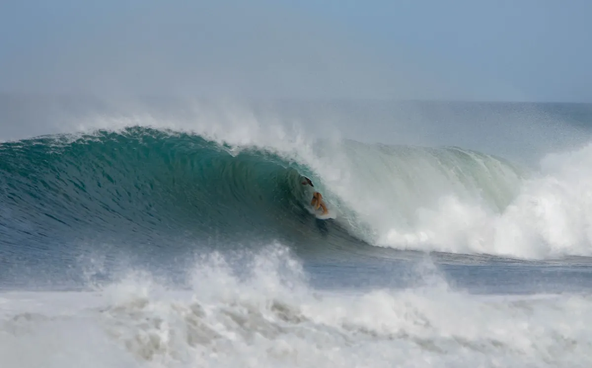 Surfer rides deep inside a powerful barreling wave.