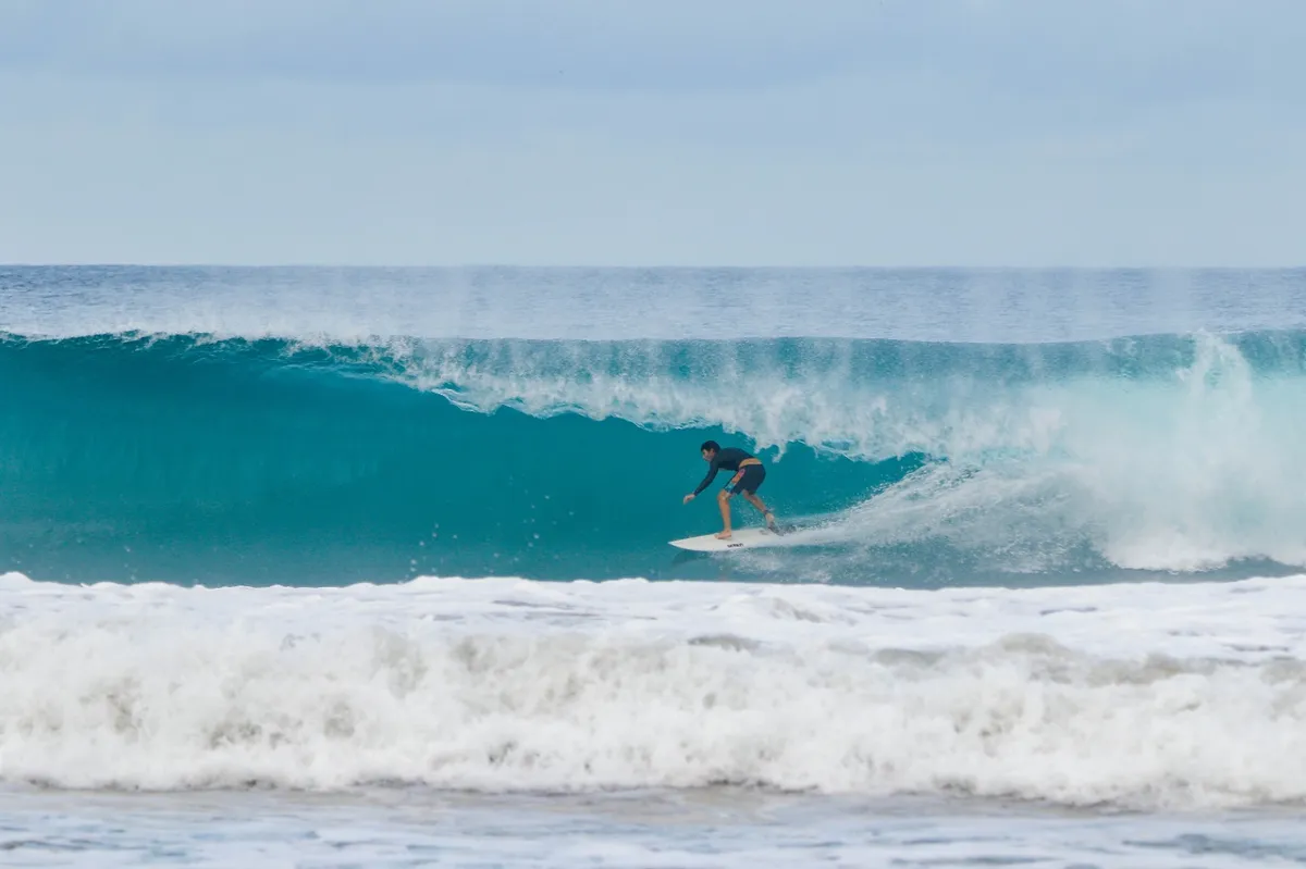 Surfer rides through a perfect blue barrel wave.