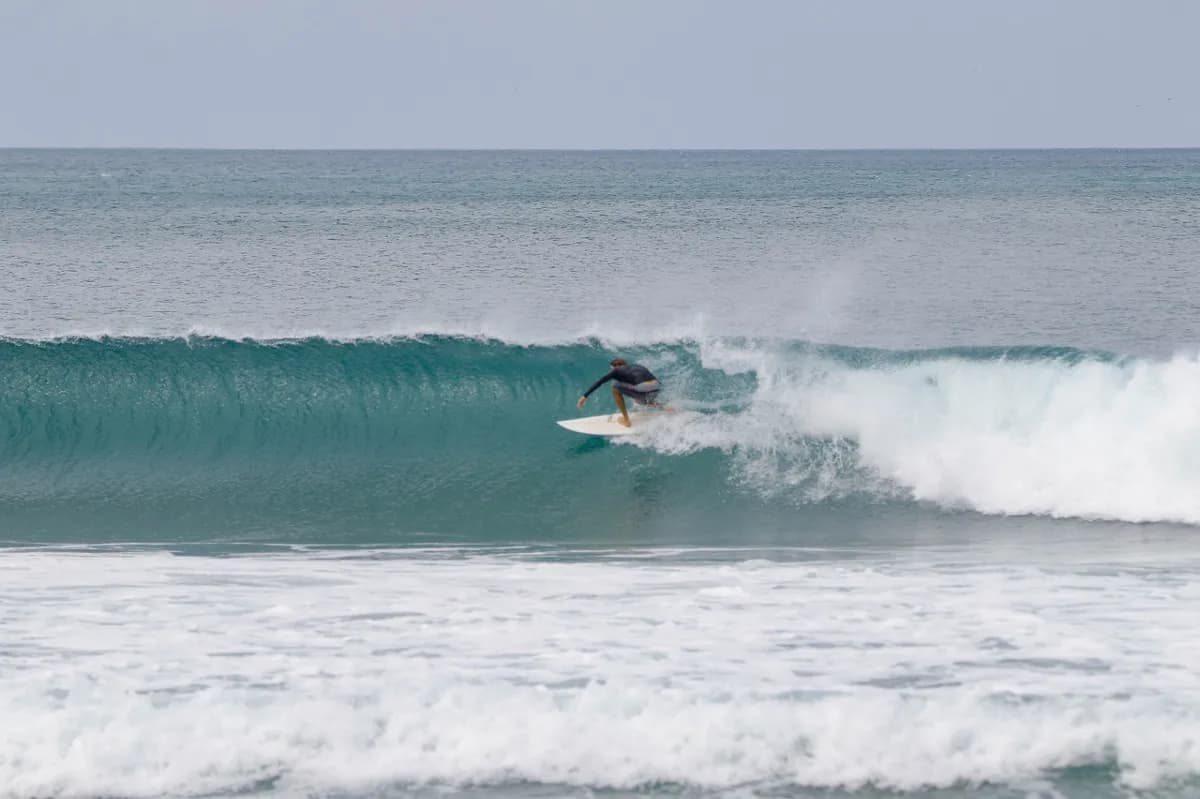 Surfer rides a perfect right barrel in clear waters.