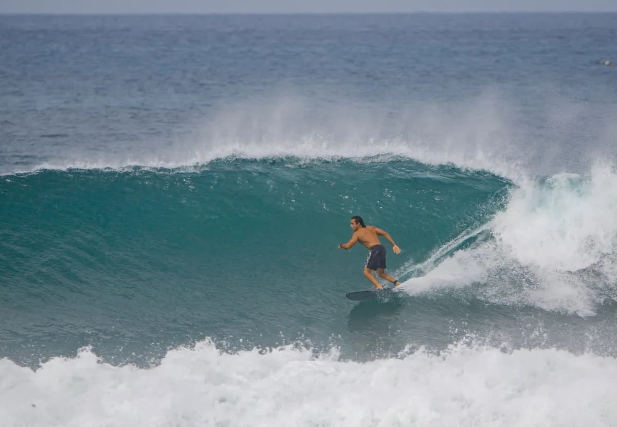 Surfer rides inside a hollow blue barrel wave.