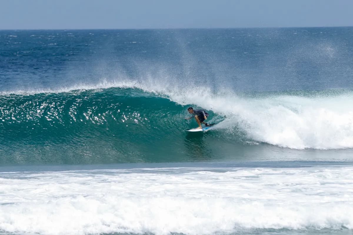 Surfer riding inside a crystal-clear barrel wave.