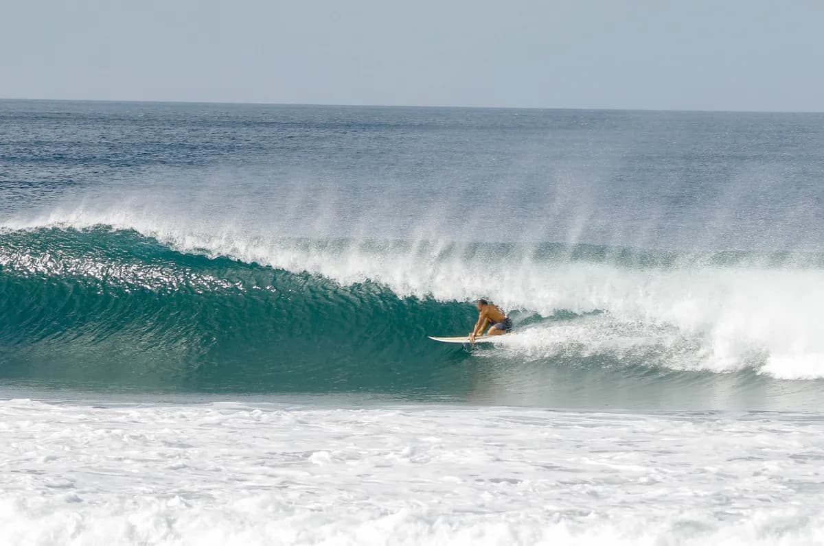 Surfer skillfully rides inside a stunning turquoise barrel.