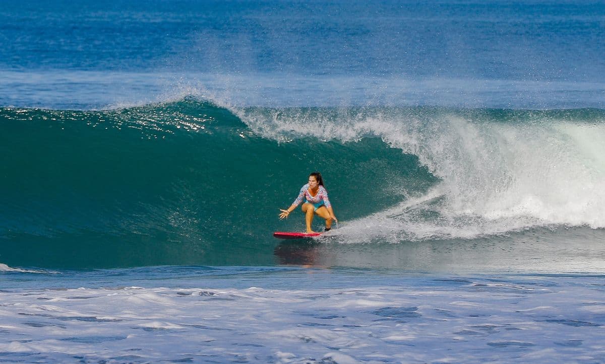 Surfer rides a perfect turquoise wave gracefully.