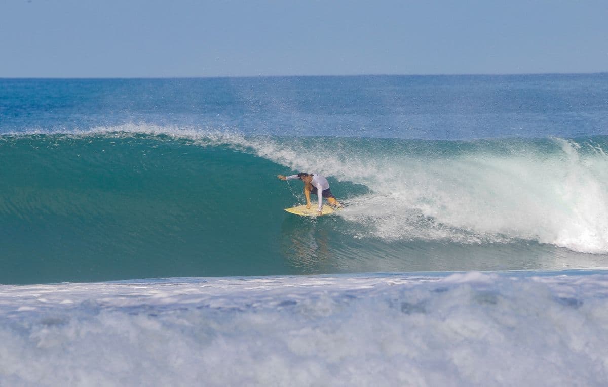 Surfer skillfully rides inside a perfect blue barrel.
