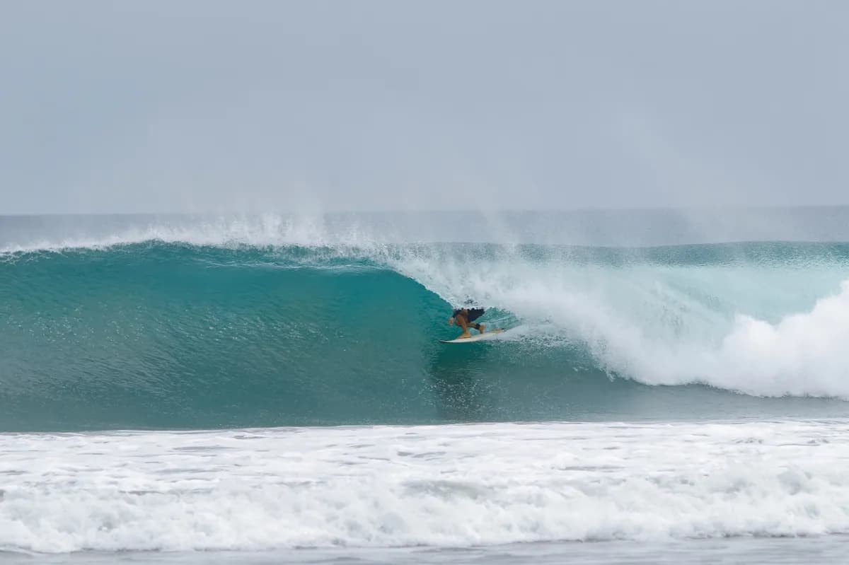 Surfer tucked inside a pristine turquoise barrel.