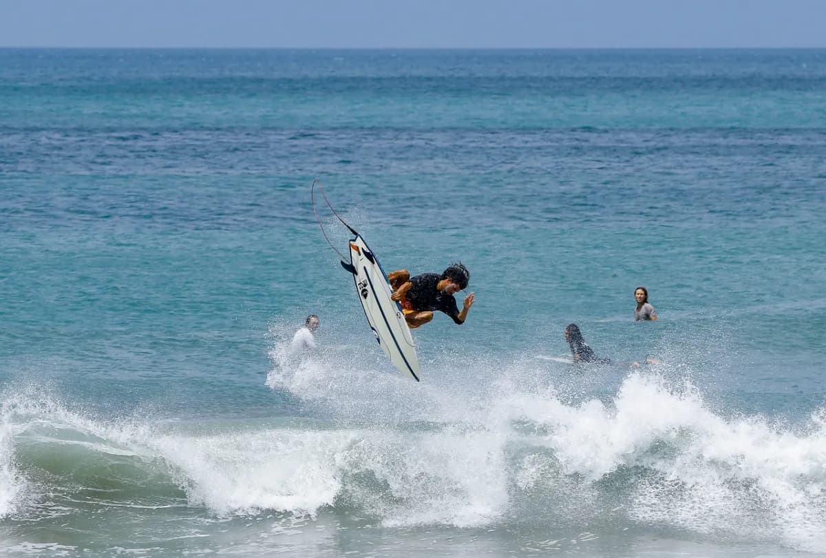 Surfer executes a high air maneuver above the wave.