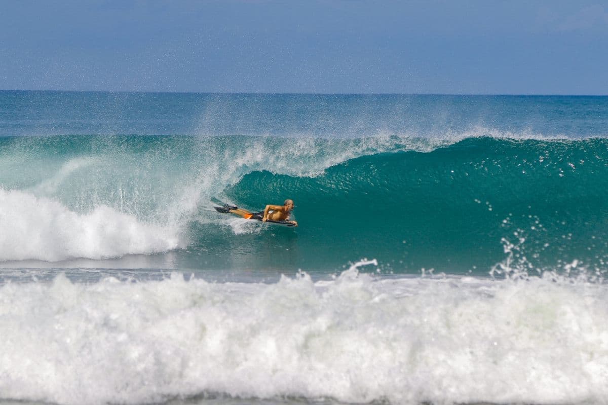Surfer rides inside a perfect blue barrel wave.