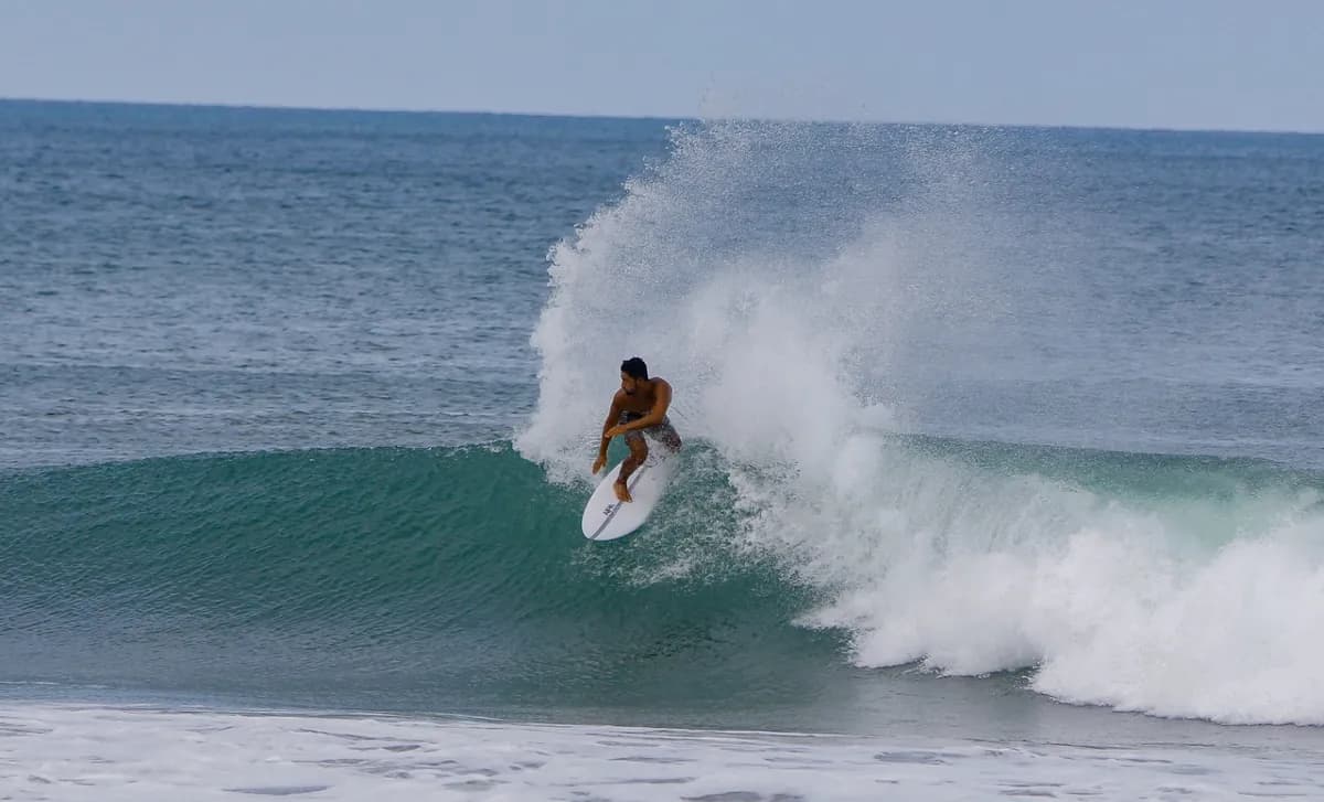 Surfer carves across a powerful wave with spray flying.