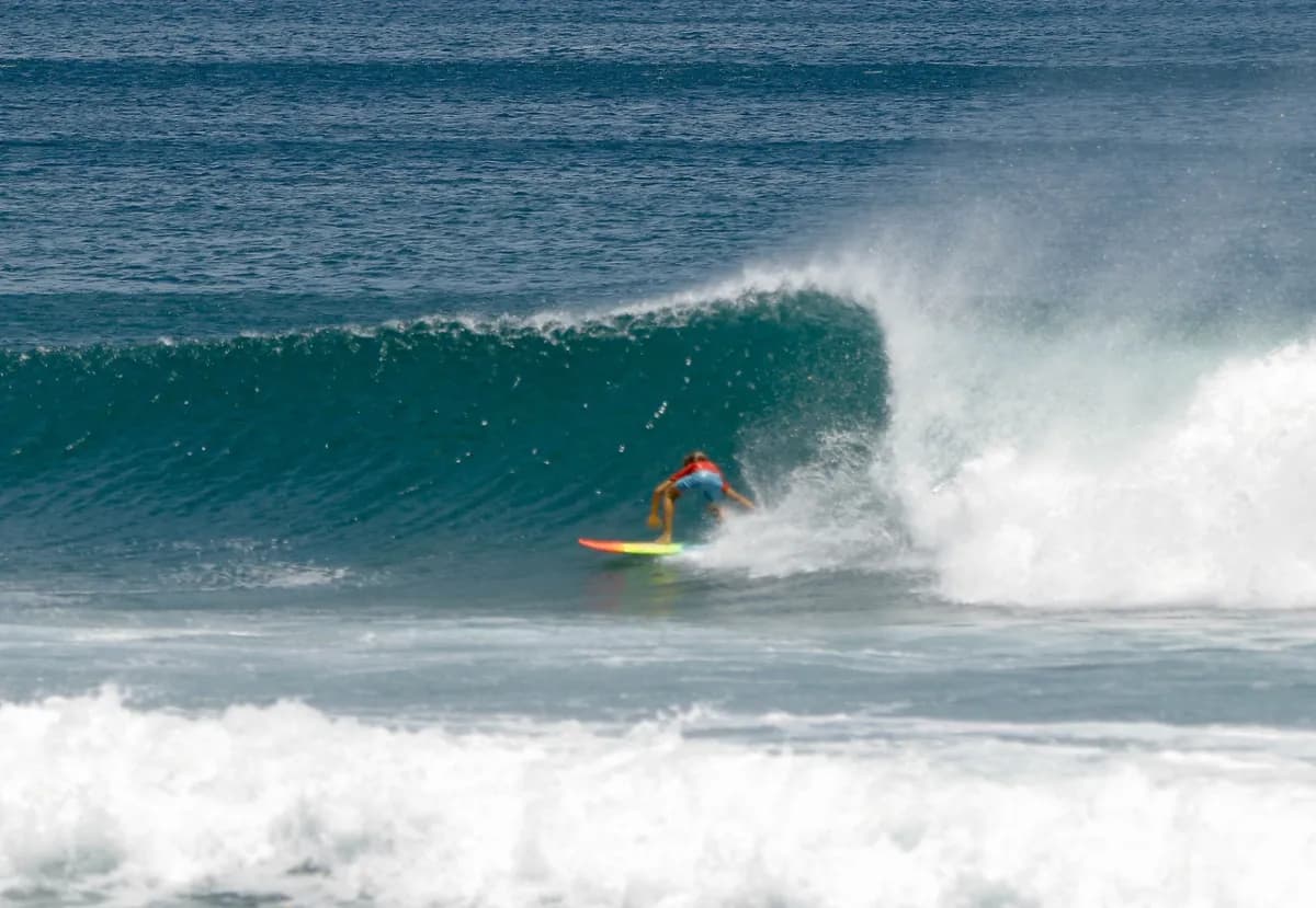 Surfer rides a vibrant green wave with expert skill.