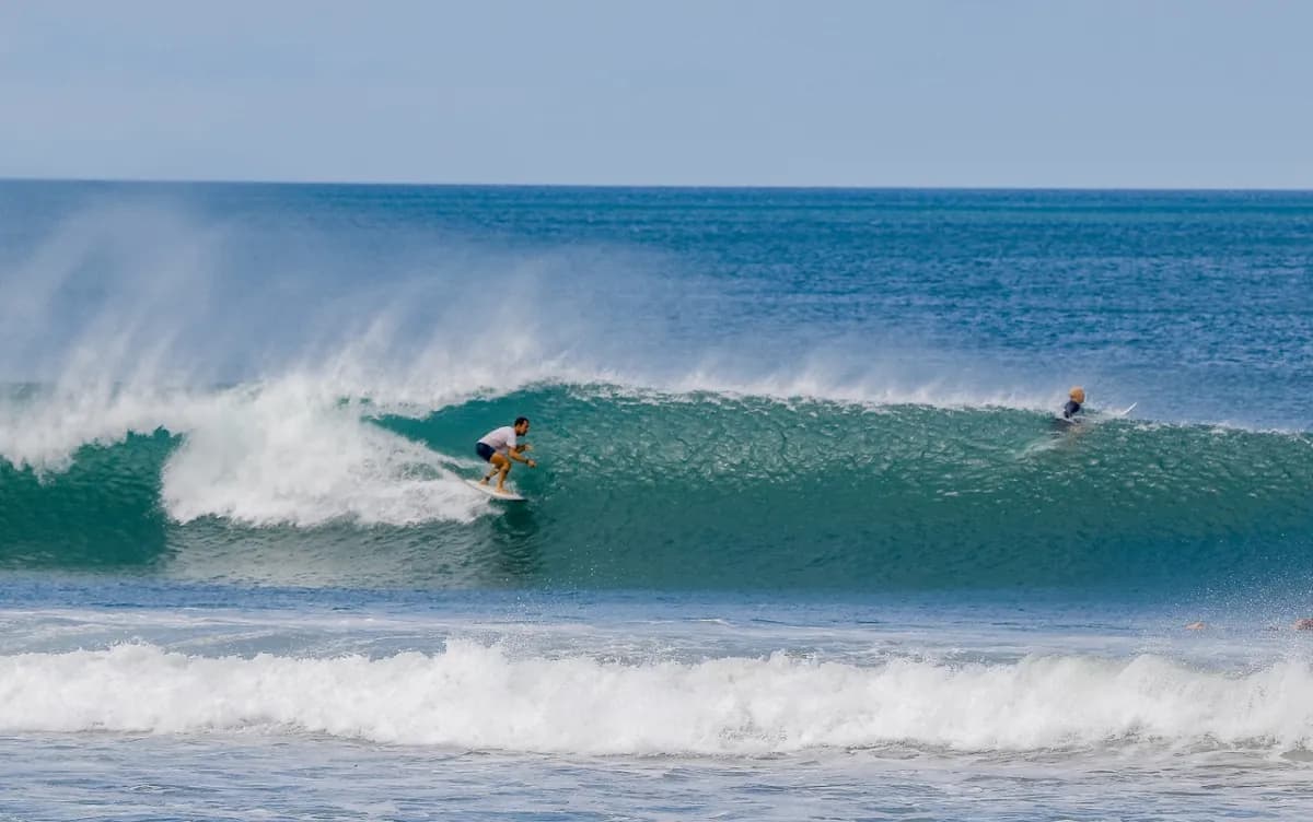 Surfer skillfully rides inside a clear green barrel.