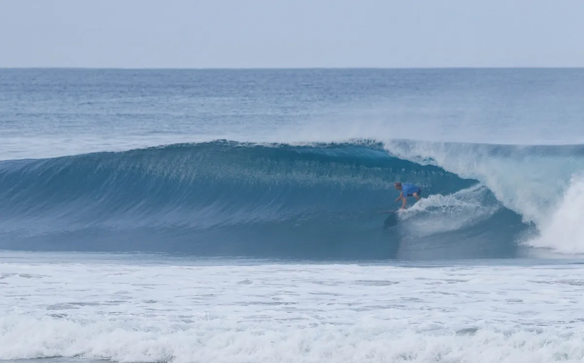 Surfer @carlos-nsr is locked in a perfect blue barrel.
