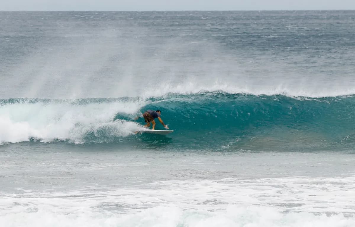 Surfer tucks into a perfectly formed barrel on a right wave.