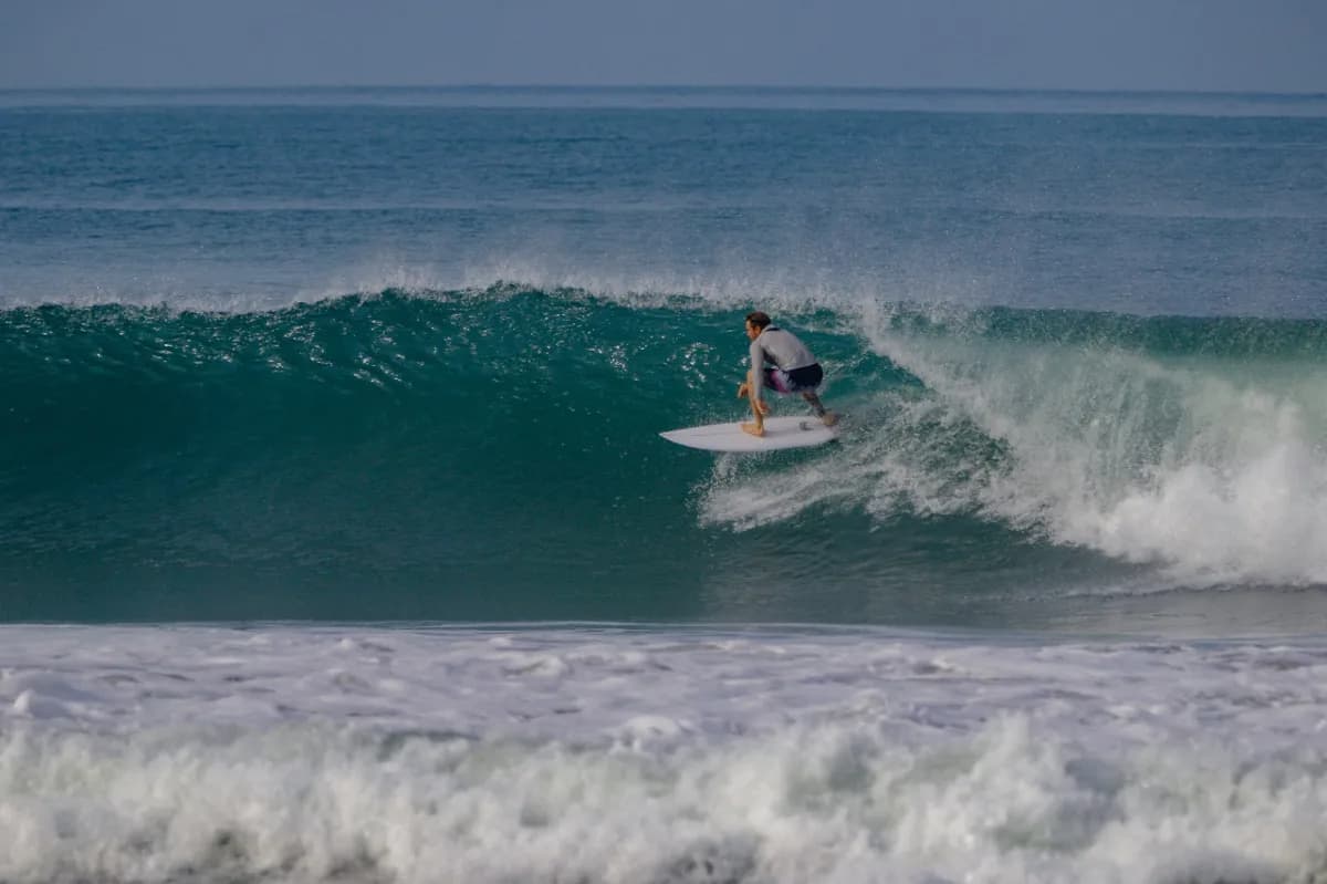 Surfer crouches inside a crystal-clear barrel.