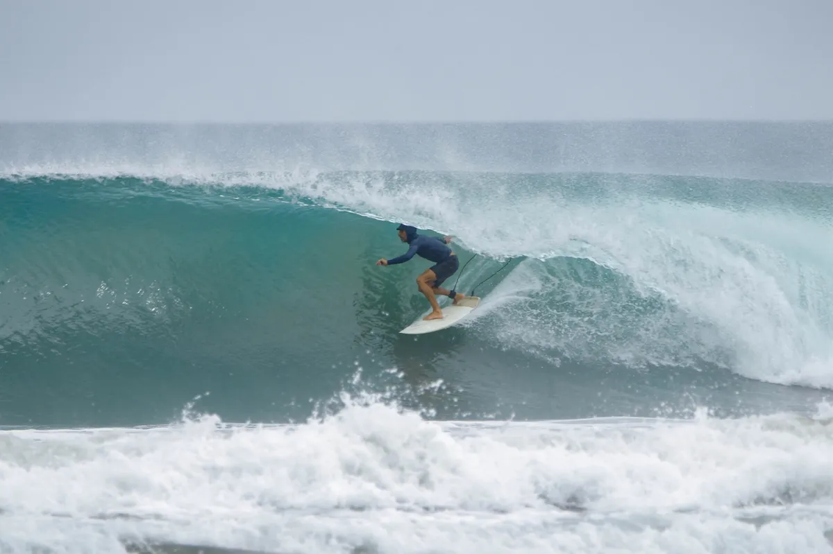 Surfer rides inside a perfect, hollow barrel wave.