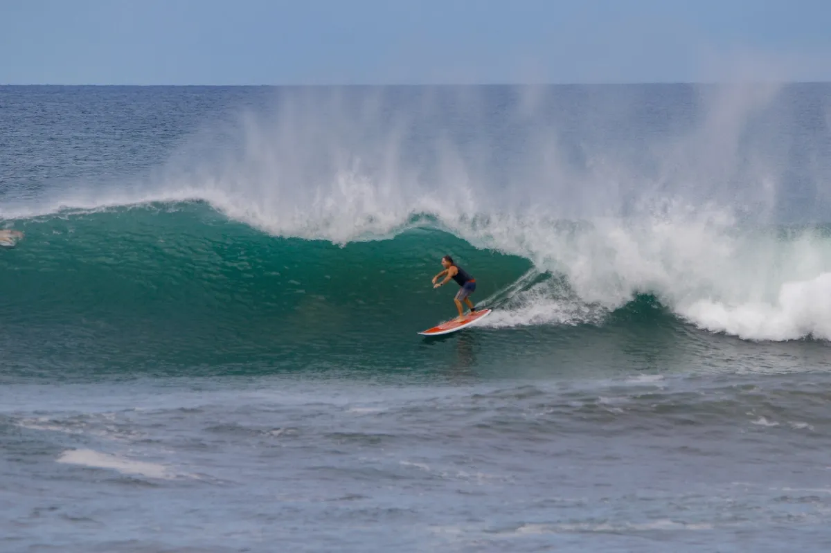Surfer rides a powerful green wave perfectly.