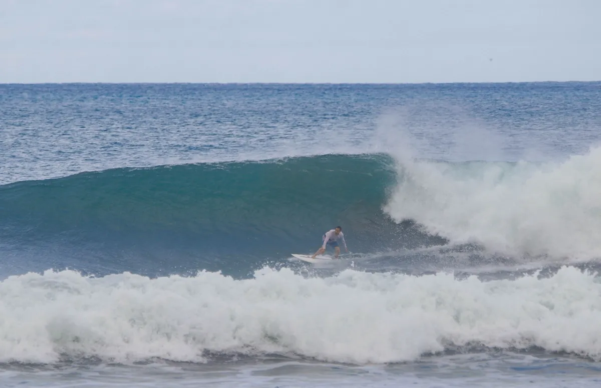 Surfer rides a clean Panga Drops barrel with focused style.