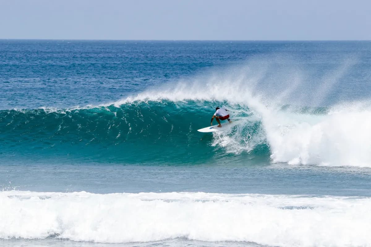 Surfer skillfully rides a blue barreling wave.