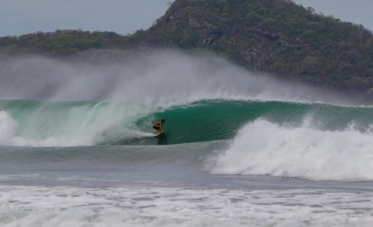 Surfer rides through a perfect emerald barrel wave.