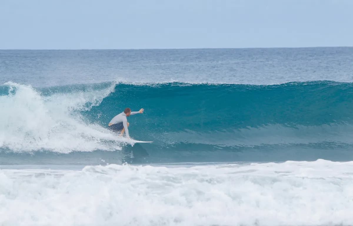 Surfer rides a hollow wave, tucked low inside the tube.