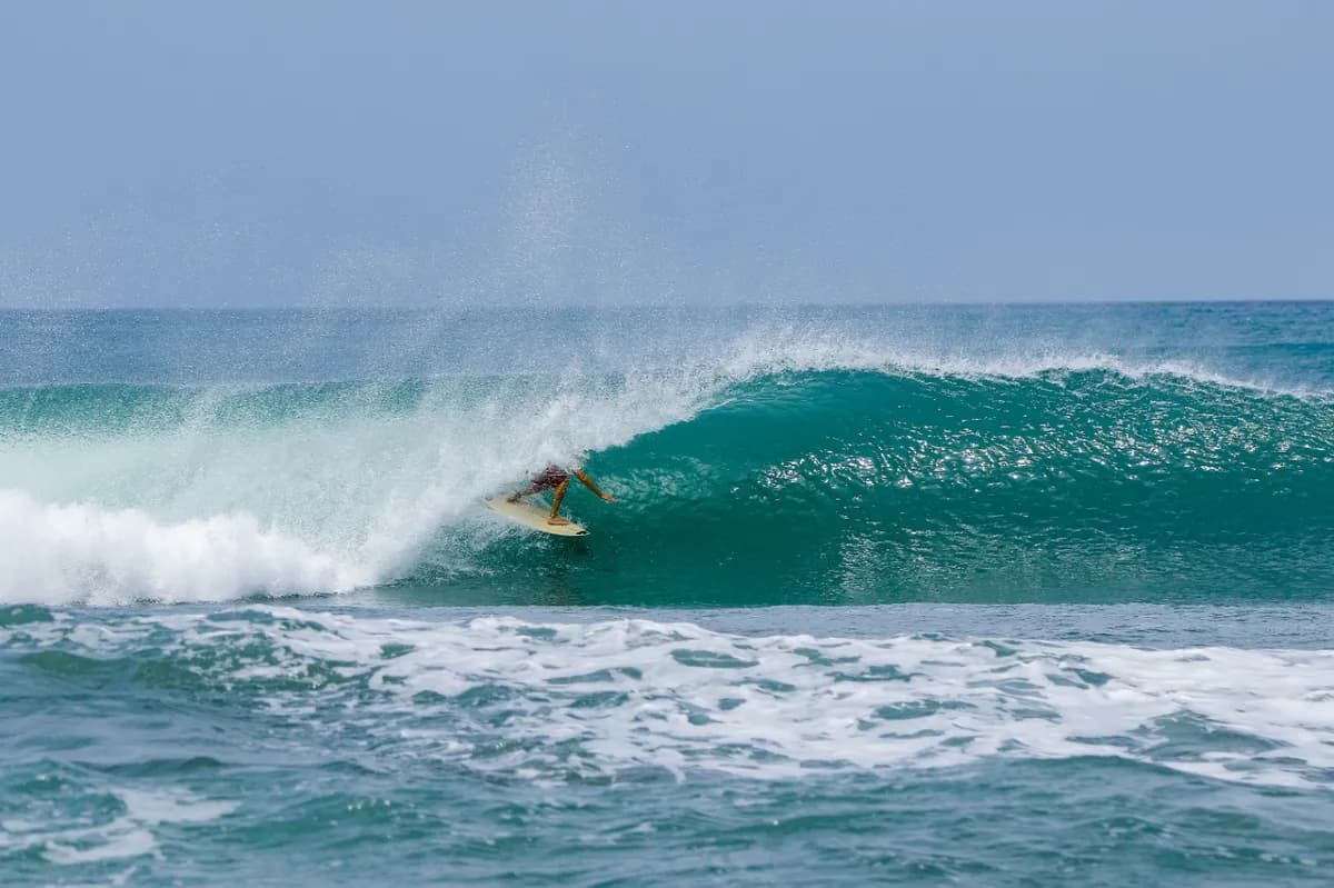 Surfer riding inside a perfect blue barrel wave.