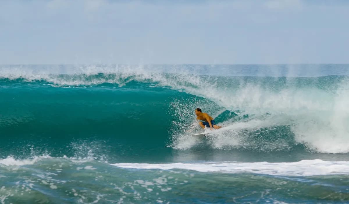 Surfer rides a pristine turquoise wave at Playa Colorado.