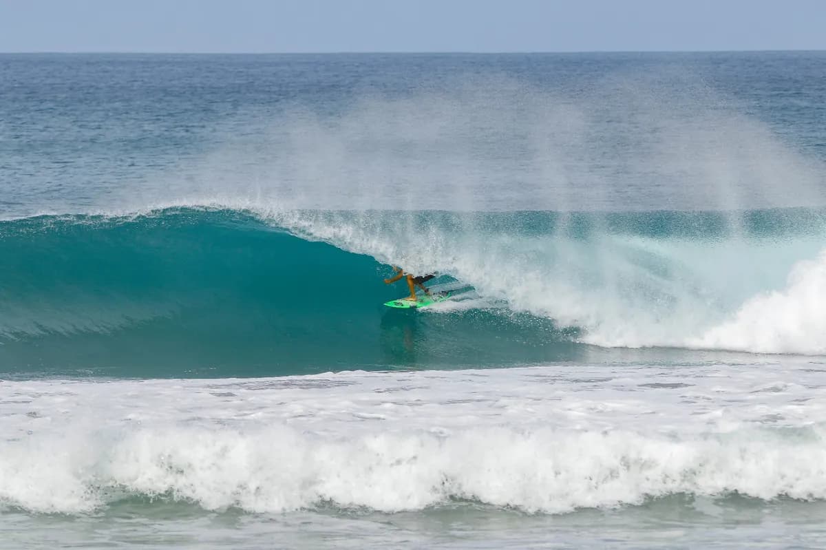 Surfer riding a perfect blue barrel wave.
