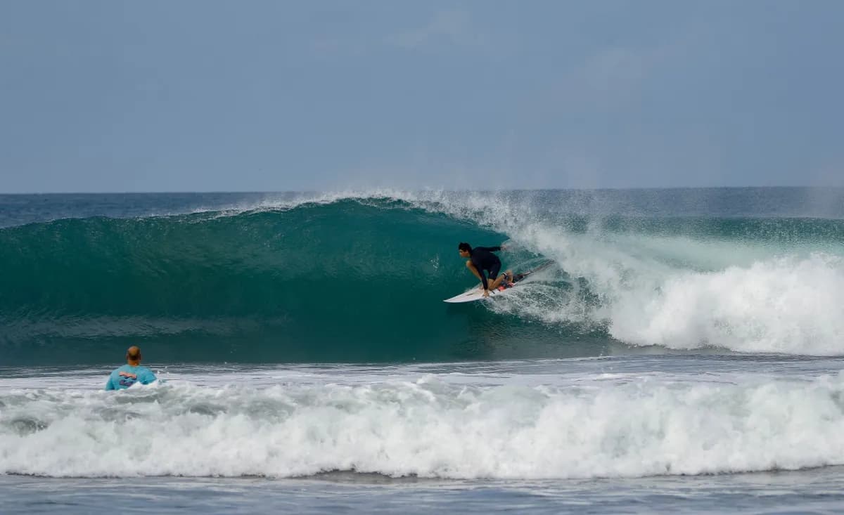 Surfer crouches inside a crystal-clear barrel.