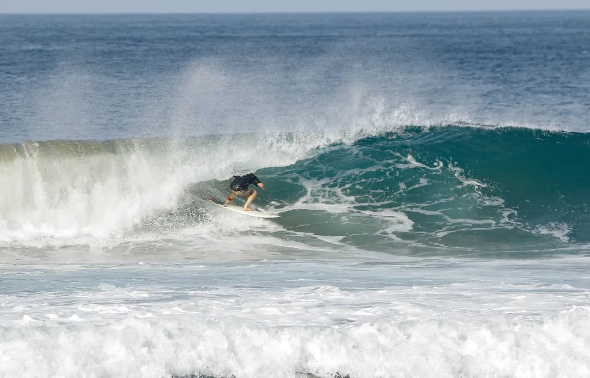 Surfer deep in a hollow wave making a bottom turn.