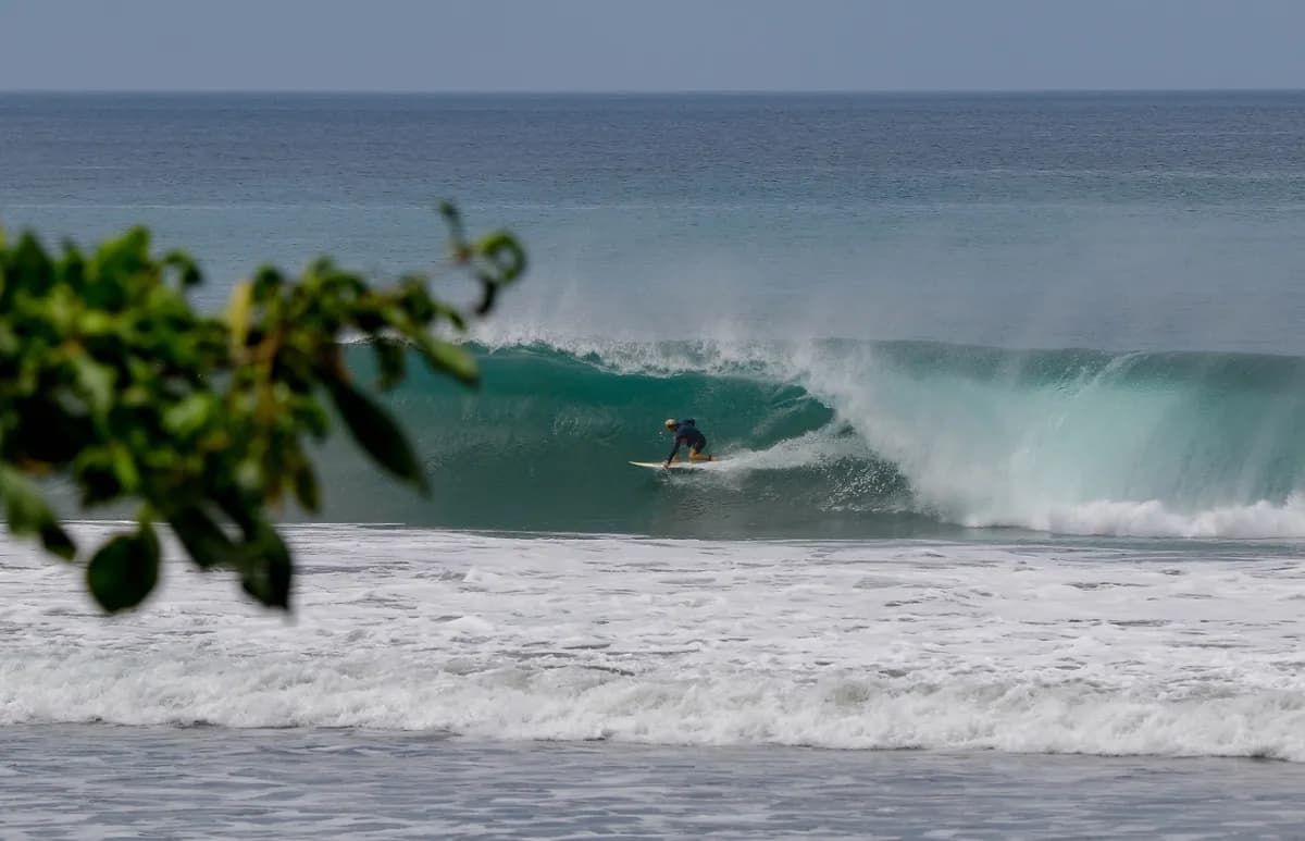 Surfer rides a powerful barrel near shore.
