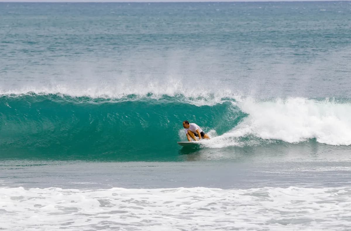 Surfer crouches inside a perfect turquoise barrel.