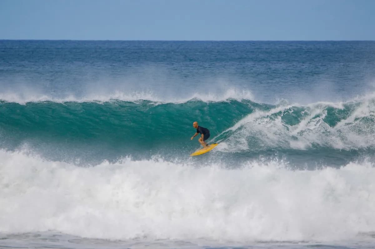 Surfer skillfully rides a large turquoise wave.