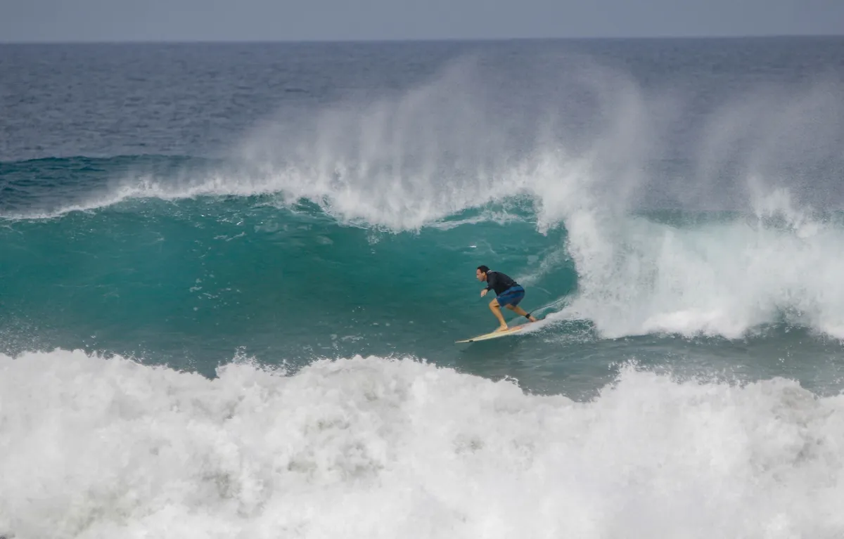 Surfer tucked into a turquoise barrel.