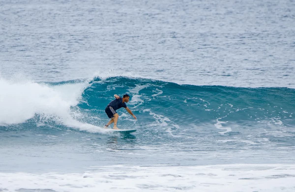 Surfer executing a precise bottom turn on a small wave.