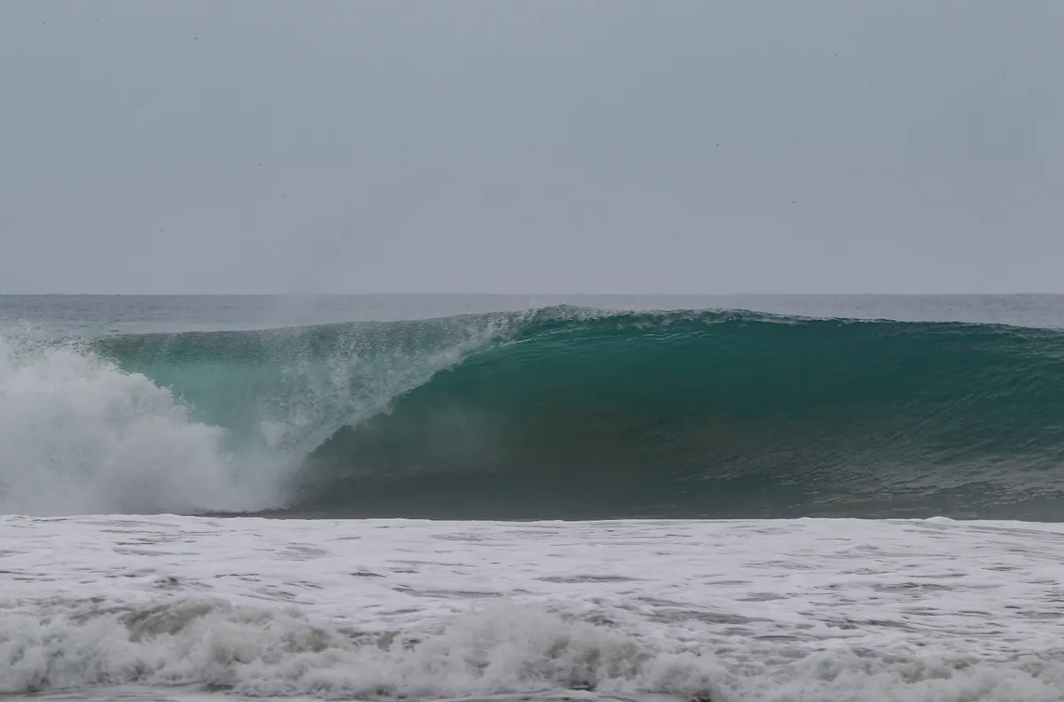 Perfectly shaped hollow wave under a cloudy sky.