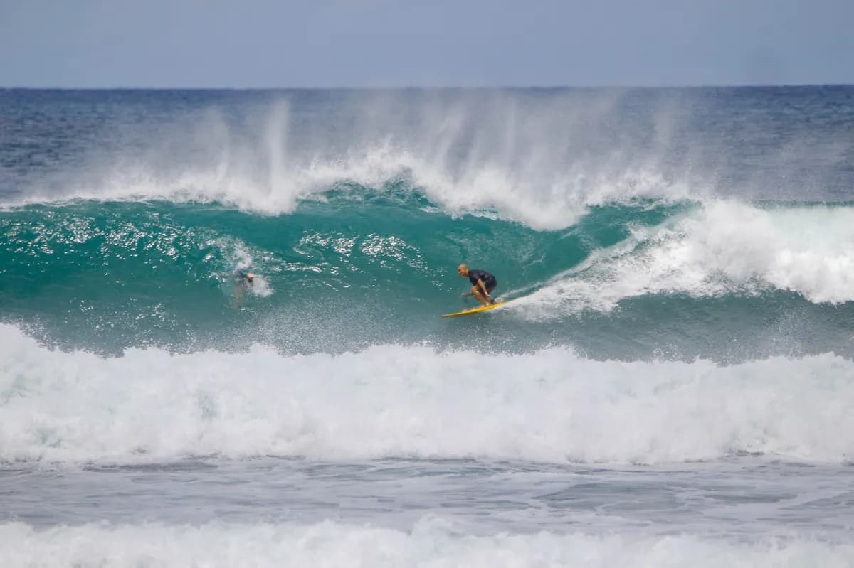 Surfer rides a hollow wave, with another surfer inside the barrel.