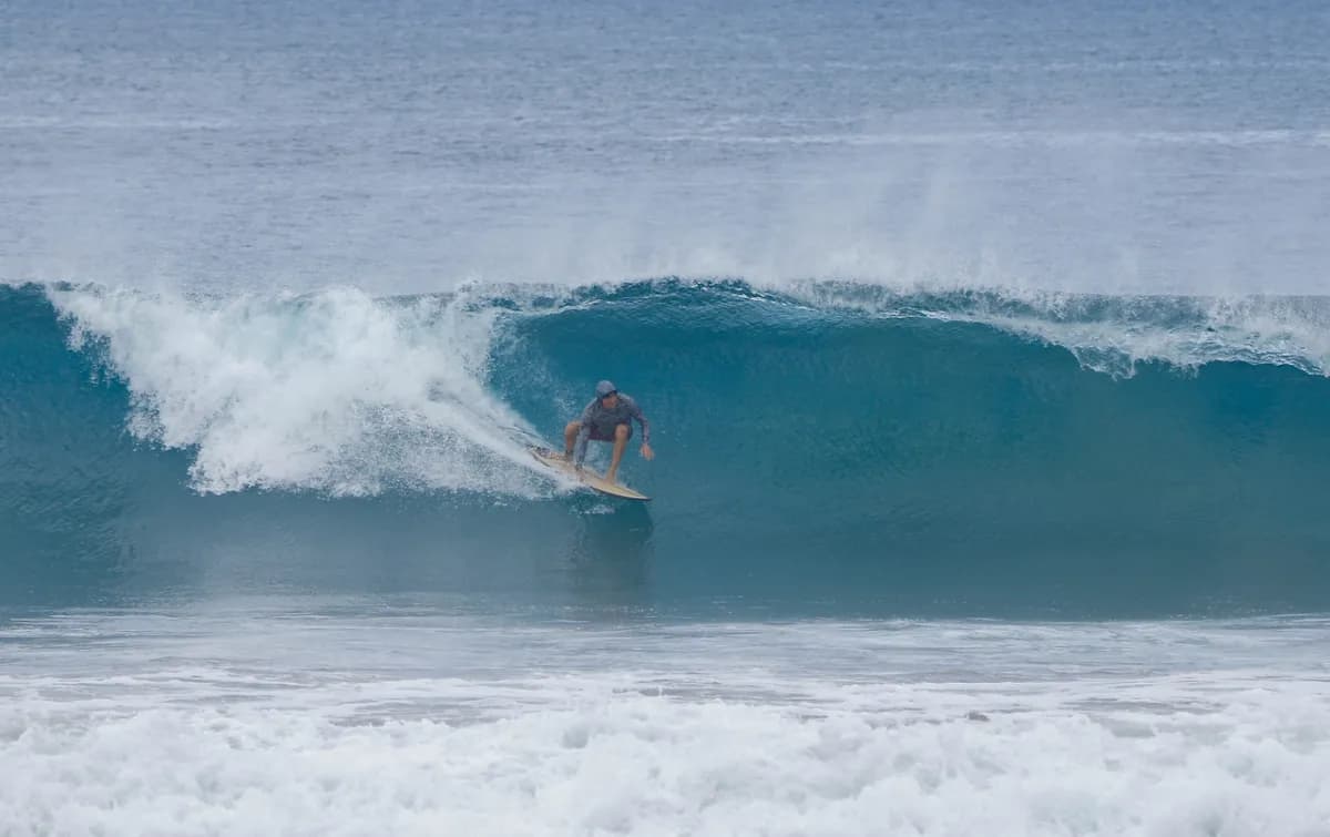 Surfer tucks into a powerful blue barrel wave.