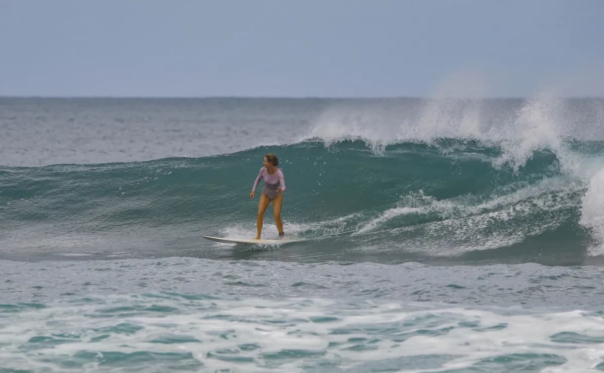 Surfer rides a clean wave, arms poised for balance.