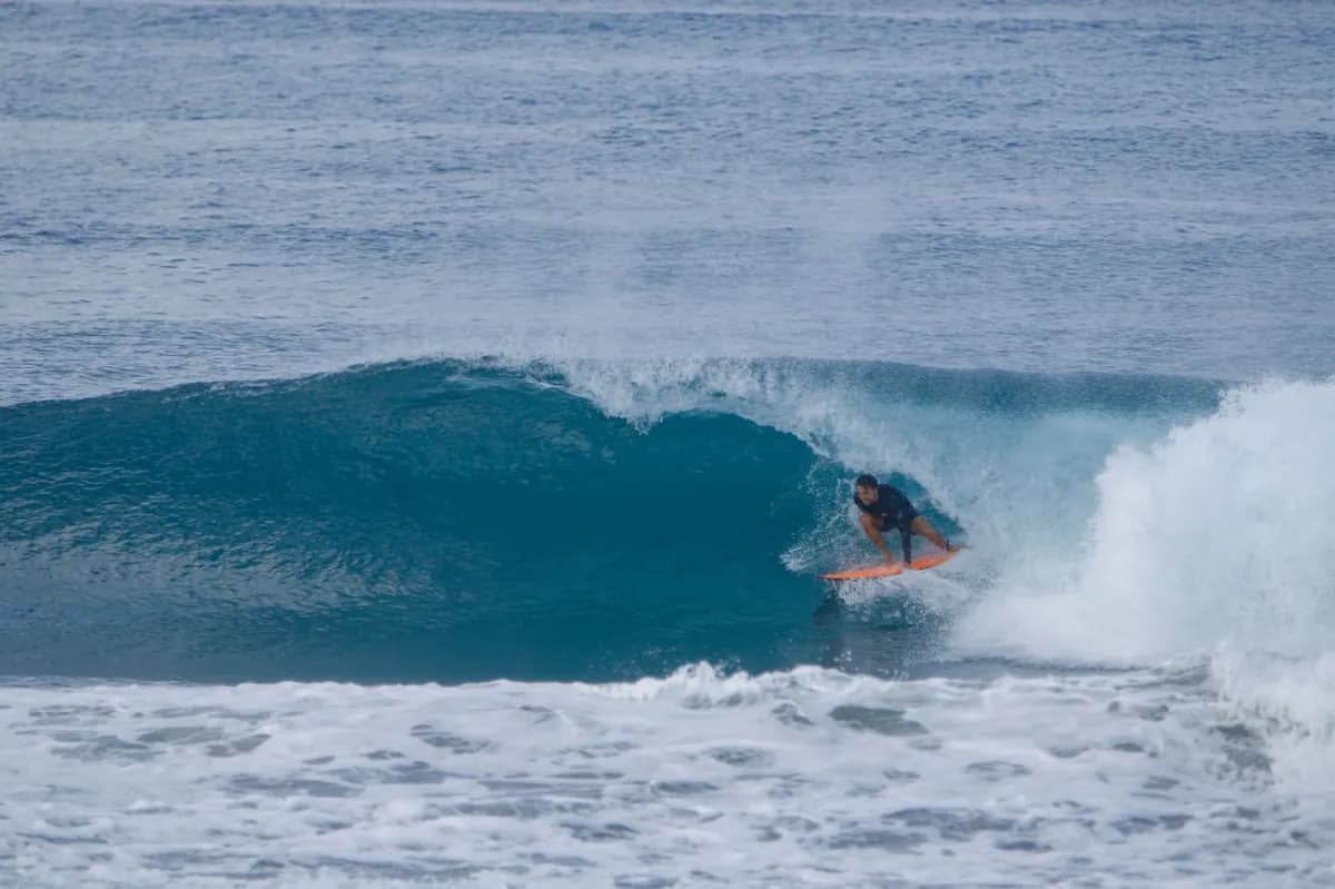 Surfer skillfully navigates a hollow barrel on a blue wave.