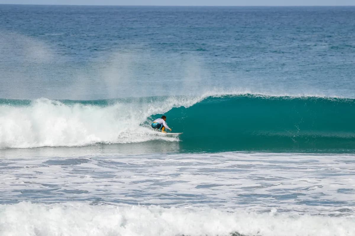 Surfer riding inside a glossy green barrel wave.