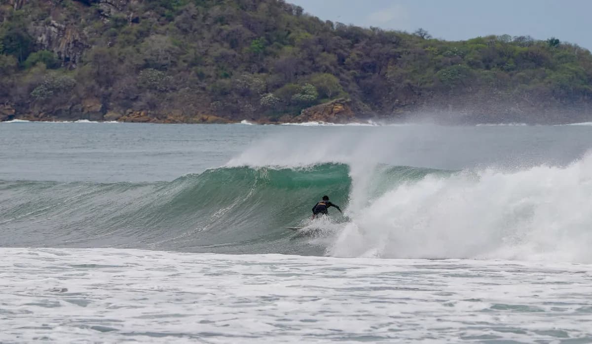 Surfer skillfully rides inside a curling wave.