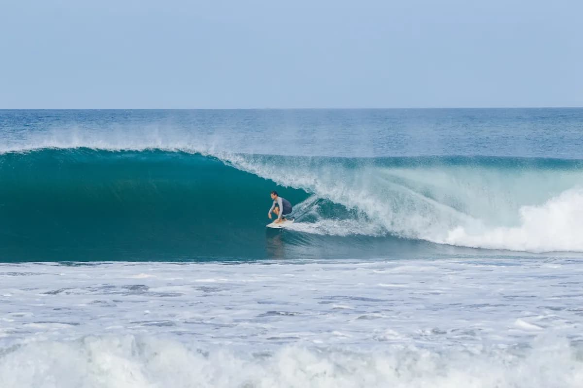 Surfer deep inside a hollow barrel on a perfect wave.