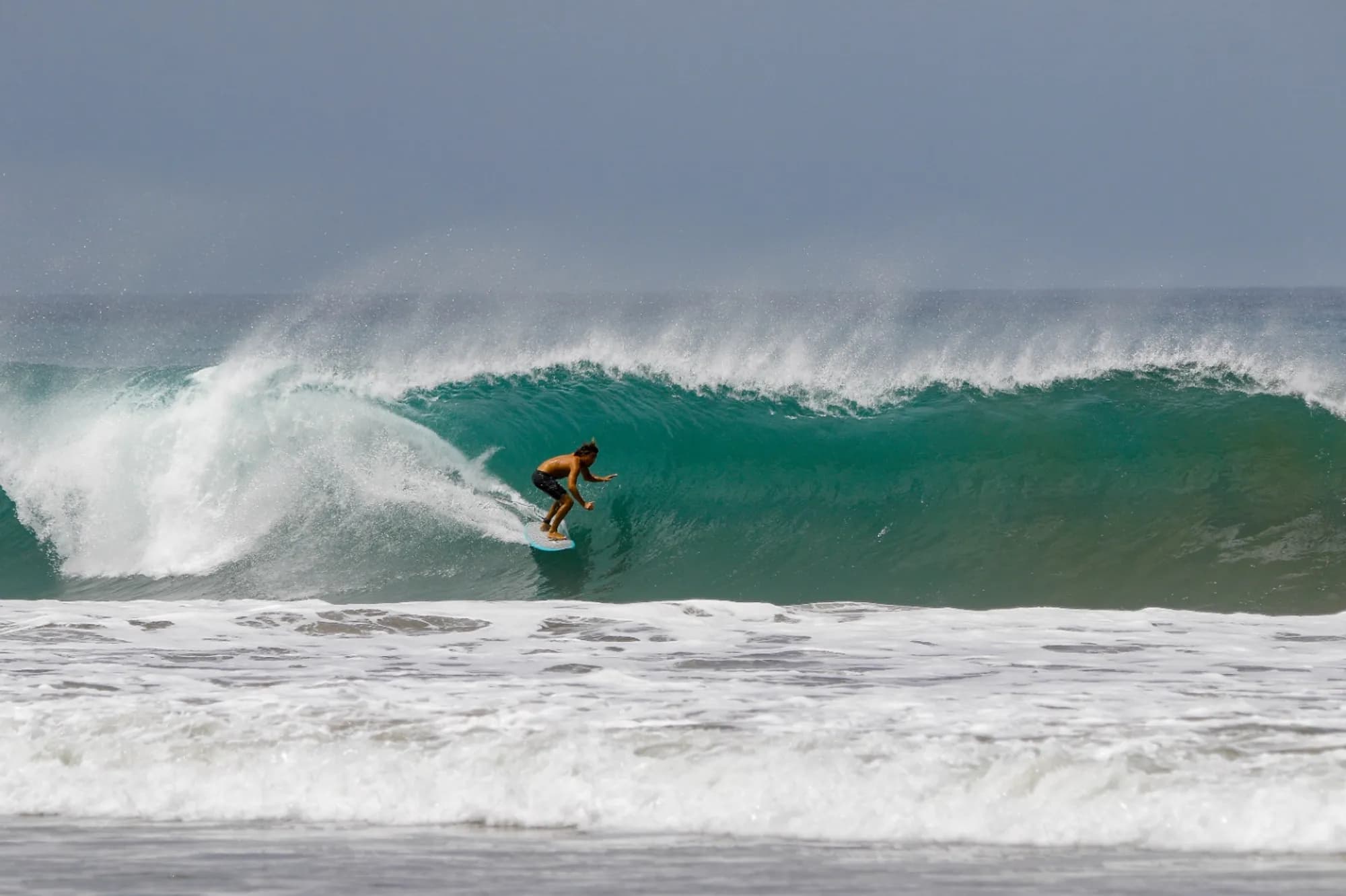 Surfer rides deep inside a powerful green barrel.
