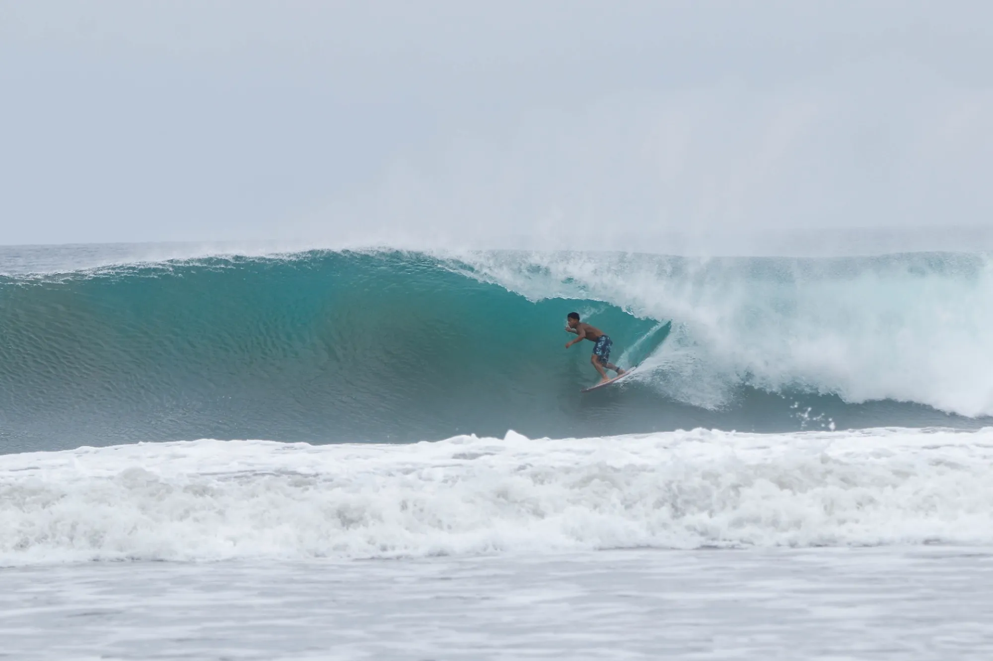 Surfer rides a perfect, blue barrel.