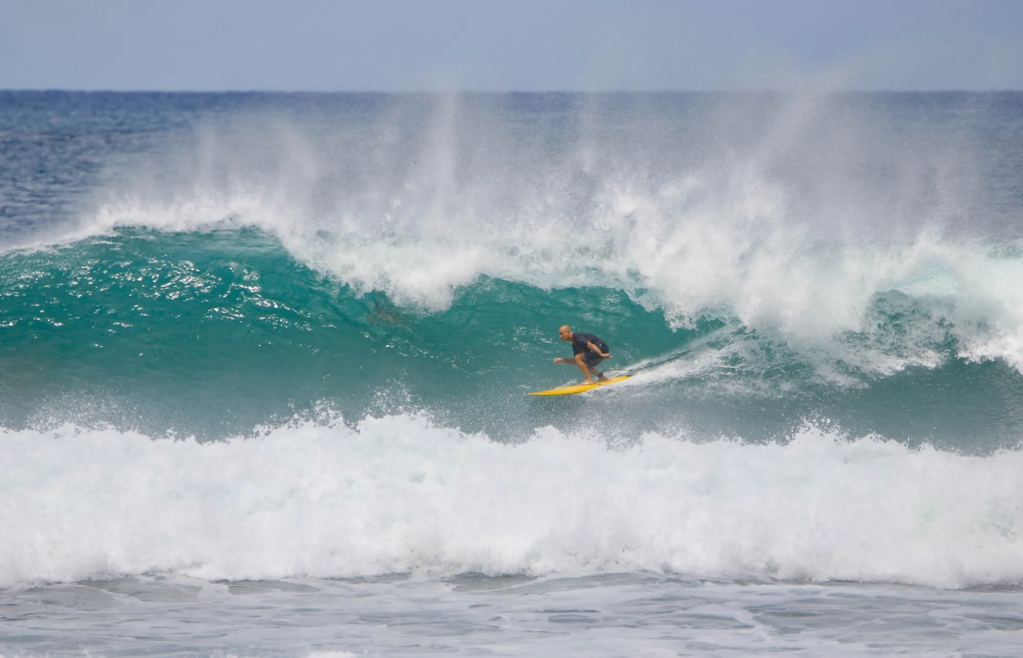 Surfer on yellow board skillfully rides a powerful wave.