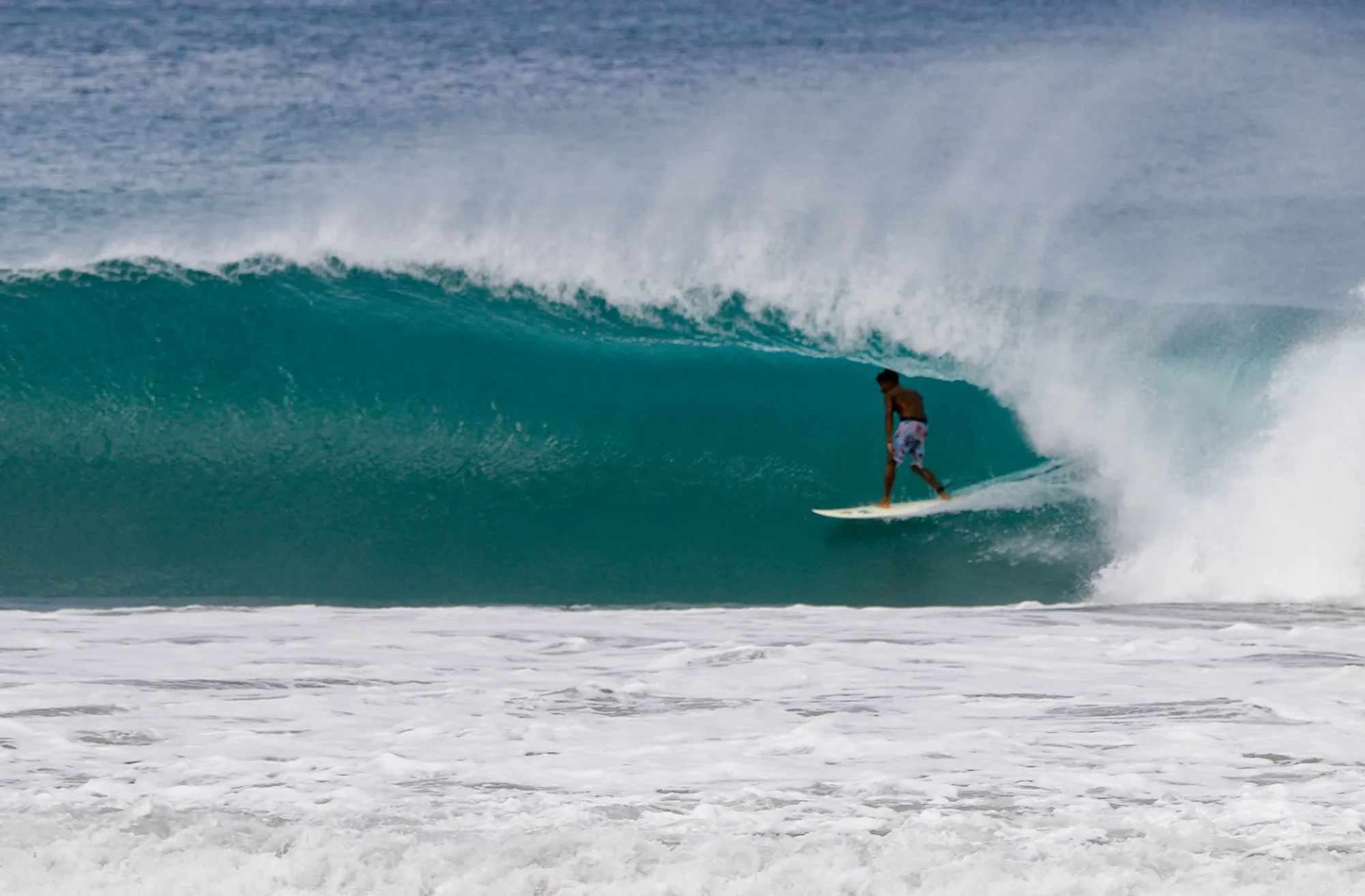 Surfer rides inside a stunning turquoise barrel.