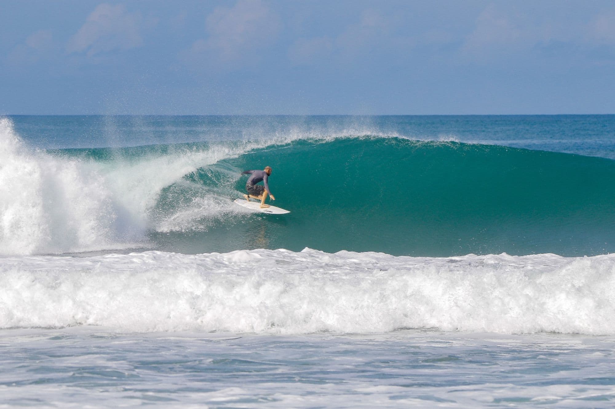 Surfer skillfully rides inside a turquoise barrel.