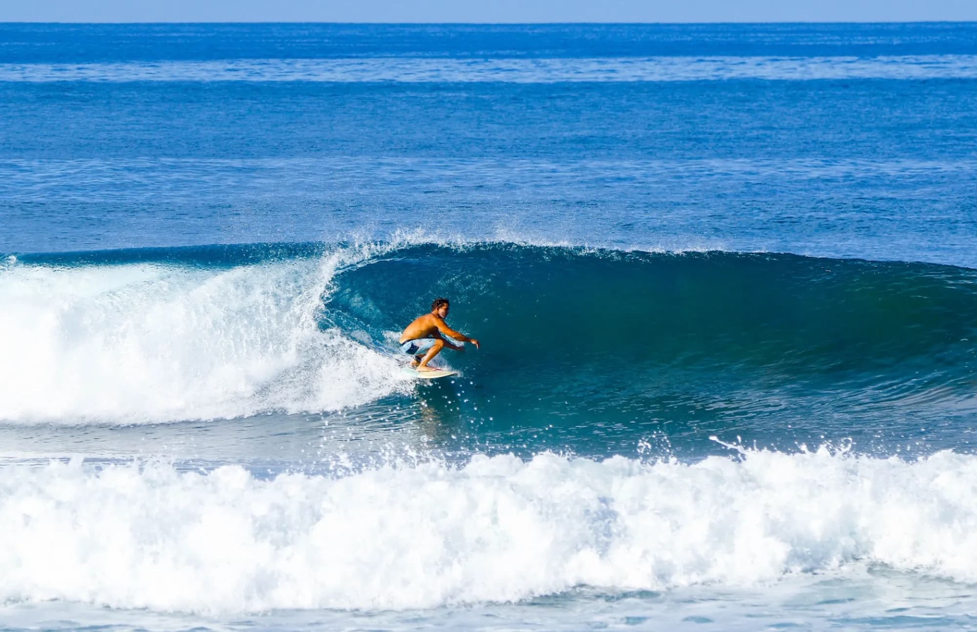 Surfer skillfully rides a clear, hollow wave.