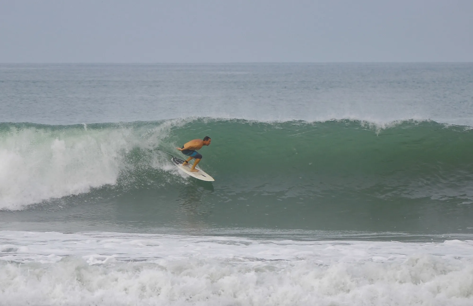 Surfer skillfully rides inside a green barrel.